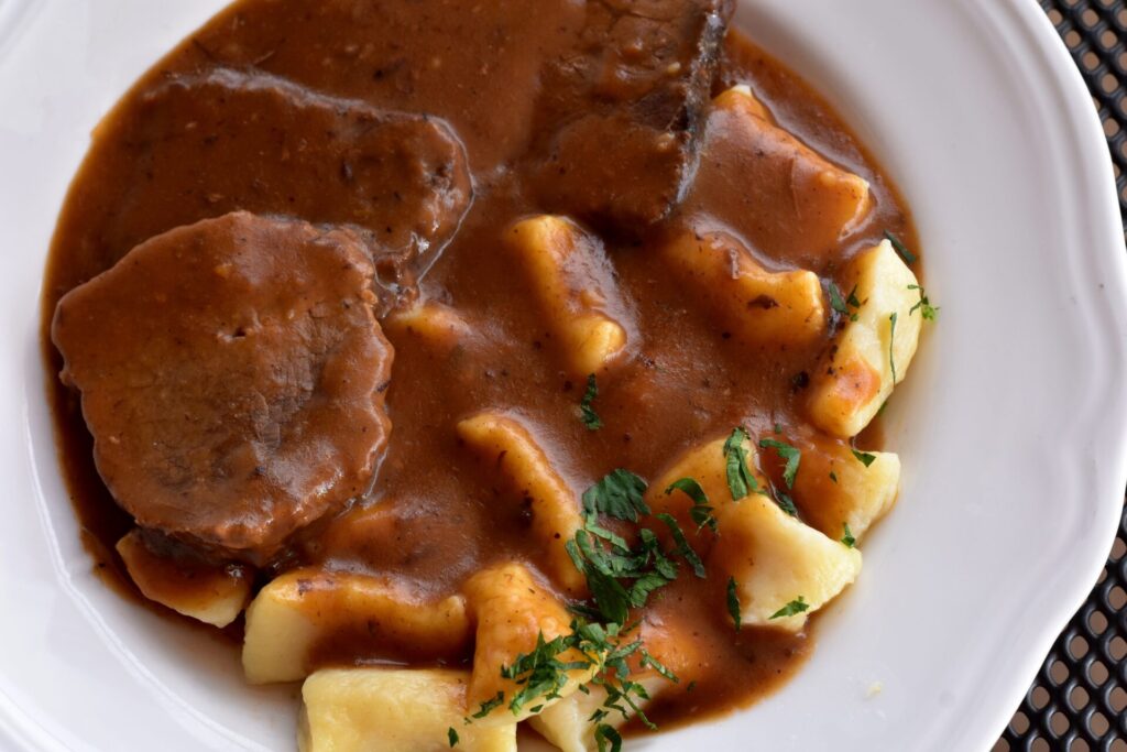 Pasticada; slow cooked beef in a rich sauce served on a plate with gnocchi