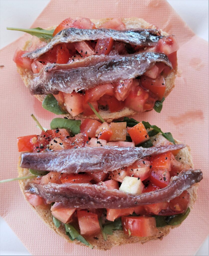 Layered bruschetta with rocket, diced tomatoes, anchovies and pepper, a local Dubrovnik food