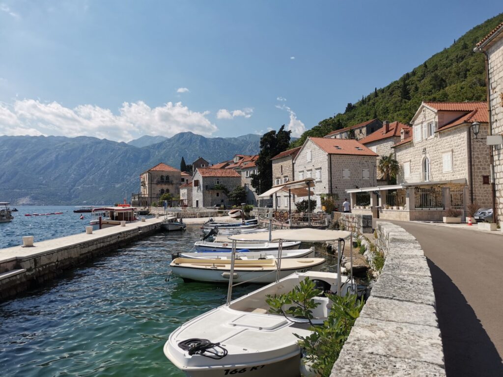 Perast waterfront with fishing boats moored up to old stone wall