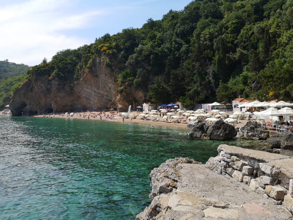 A sunny day overlooking Mogren beach with a sandy beach and clear waters in Budva, Montenegro