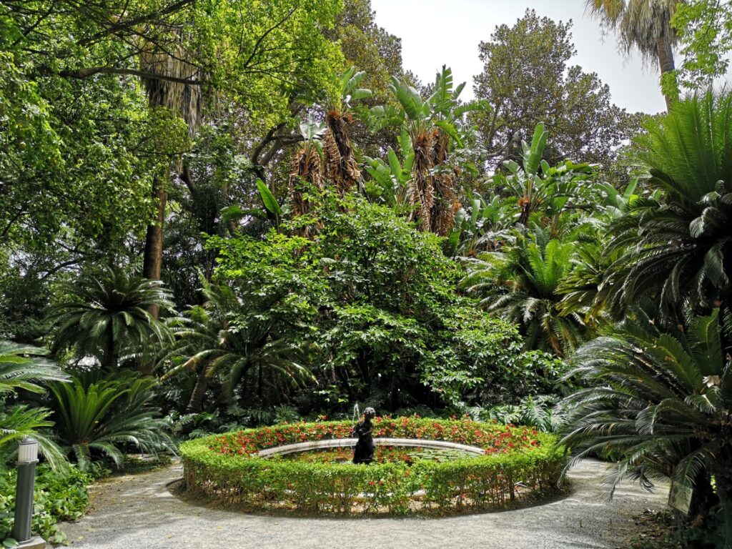 Lush greenery covers a circular monument at the Botanical Gardens in Malaga, Spain