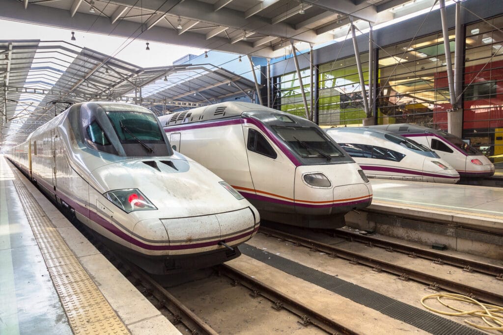 Renfe Spain high speed rail trains in a Spanish train station. Alvia train on the left hand side, AVE train 3rd train in from the right, used to get the Madrid to Seville train