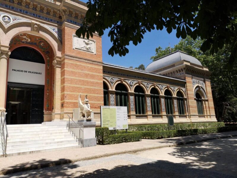 A red brick building with arched windows and ornate mosaic details which is now used as an art exhibition space in El Retiro park, Madrid, Spain