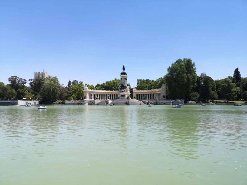 The lake with Al Fonso monument behind on a sunny day in El Retiro Park, Madrid, Spain