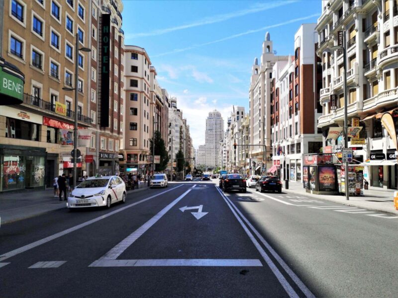 A perspective view down Gran Via in Madrid, Spain with blue skies and towering buildings either side of the main road