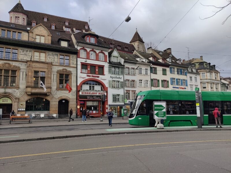 Basel old town buildings with a bright green tram of the city running through