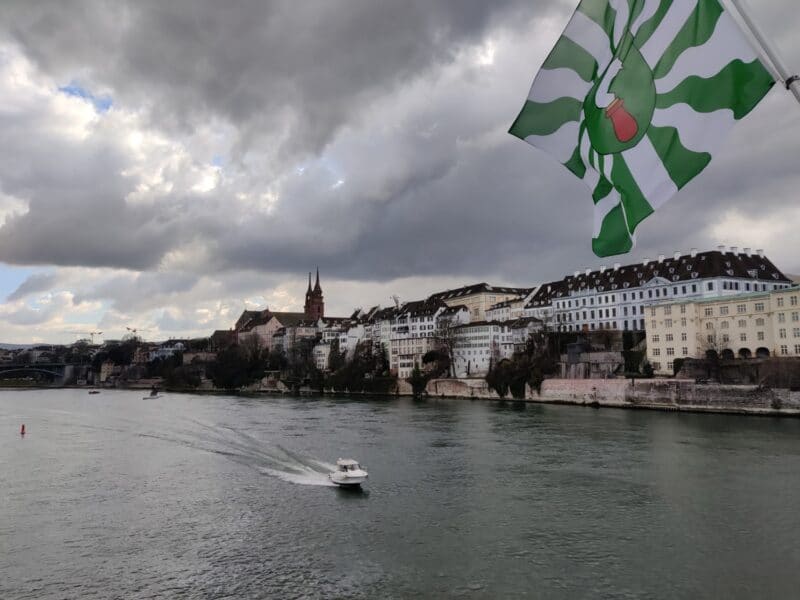 The Rhine river running through Basel city on cloudy day with a speedboat enjoying the scenery of Basel old town on either side